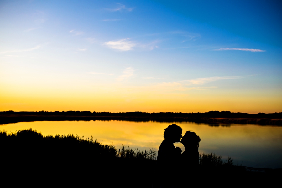 A silhouette of a newly married lesbian couple in the setting sun on their wedding day.